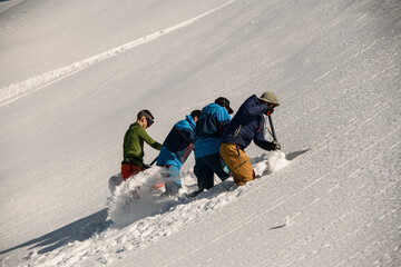 men are digging snow and checking the mountain for avalanche safety. Making schurf - obrazy, fototapety, plakaty