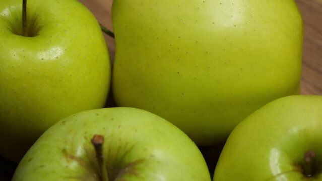 Four apples of the Reinette Simirenko variety on a wooden surface, close-up. Rotating fruits.
