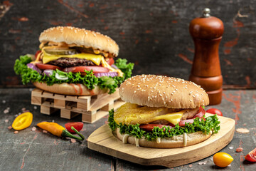 Tasty grilled homemade burgers with beef, tomato, cheese, bacon and lettuce on rustic wooden background. fast food and junk food concept