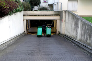 Gardienne d'immeuble qui rentre les poubelles