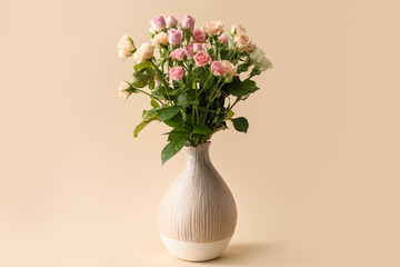 Vase with bouquet of beautiful roses on beige background