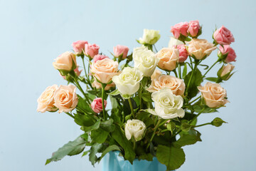 Vase with bouquet of beautiful roses on color background