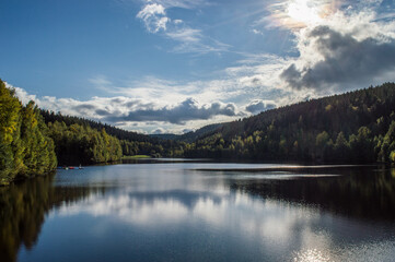 Fototapeta premium dam with blue sky and clouds on a beautiful day in fall with reflections on water