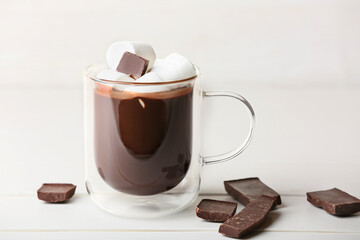 Glass cup of tasty hot chocolate with marshmallows on light background