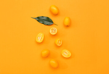 Tasty kumquat fruits on orange background