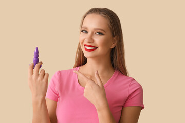 Young woman with butt plug on light background