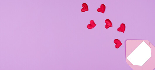 pink envelope and hearts that fly out of it on a purple background flat lay