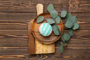 Composition with bath bomb and eucalyptus branches on wooden background