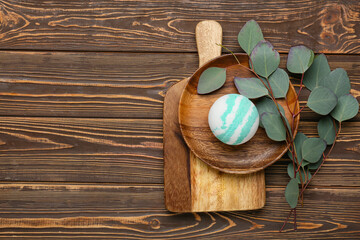Composition with bath bomb and eucalyptus branches on wooden background