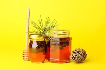 Jars of tasty pine cone jam on yellow background