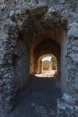 Fototapeta na wymiar Ruins of stone gate through a thick wall to the ancient Fortress of Villehardouin, Mystras, Greece