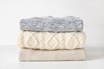 Stylish baby sweaters on light background