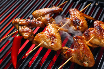 Tasty chicken wings skewers on grill