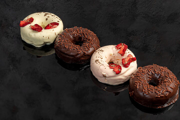 Handmade donuts on a light background in white and black chocolate. There are flowers nearby....
