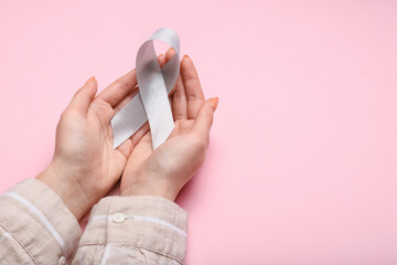 Woman with Parkinson's awareness ribbon on pink background