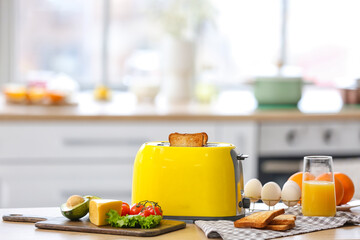 Yellow toaster with healthy food on table in light kitchen