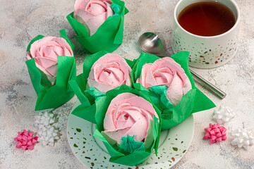 Handmade marshmallows on a light background in the form of roses, hydrangeas and tulips. There are...