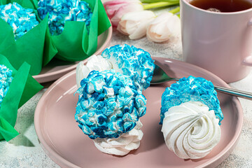Handmade marshmallows on a light background in the form of roses, hydrangeas and tulips. There are...