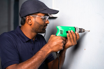 Electrician drilling wall using drilling machine - concept of home renovation, skilled profession...