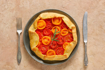 Plate with tasty tomato galette on beige background
