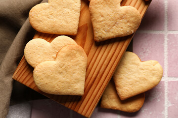 Wooden board with tasty heart shaped cookies on table, closeup. Valentines Day celebration