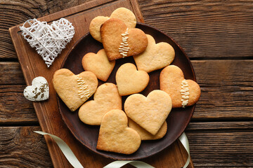 Fototapeta premium Plate with tasty heart shaped cookies on wooden background. Valentines Day celebration