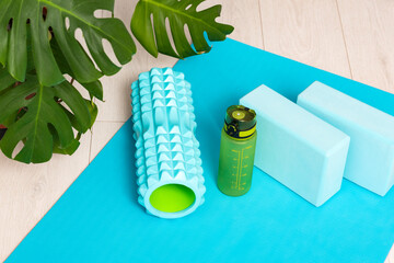Workout at home. Foam roller for massage of muscle and fascia, gym blocks and a bottle of water. Sport equipment.