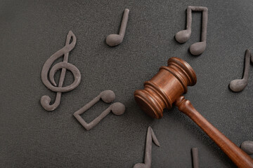 Judges gavel surrounded by treble clef and notes on black background. Violation of music license and copyright. Music piracy.