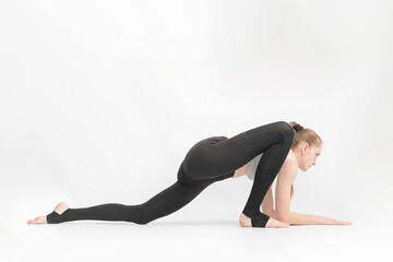 Fototapeta premium Young slender gymnast girl does an exercise to develop flexibility on white background. Asanas in yoga.