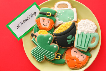 Obraz premium Plate with tasty gingerbread cookies for St. Patrick's Day celebration on red background