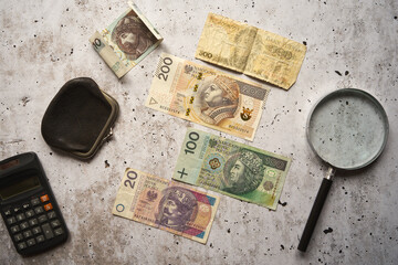 monety, banknoty ,kalkulator ,lupa i czarna portmonetka  na betonowym stole ,polski złoty 