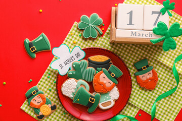 Composition with tasty gingerbread cookies for St. Patrick's Day celebration and calendar on red background