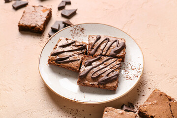 Plate with pieces of tasty chocolate brownie on beige background