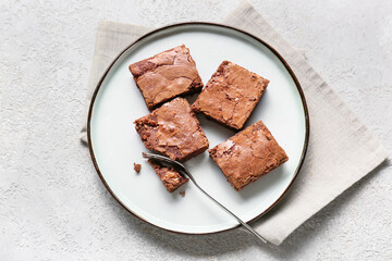 Plate with pieces of tasty chocolate brownie on light background