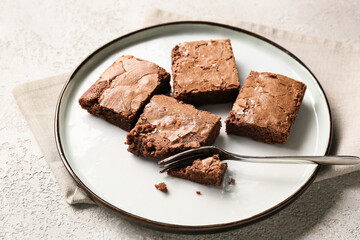 Plate with pieces of tasty chocolate brownie on light background