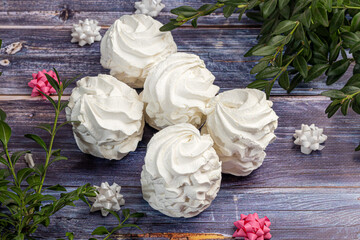 Handmade marshmallows on a light background in the form of roses, hydrangeas and tulips. There are...