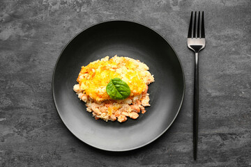 Plate with tasty English fish pie on black background