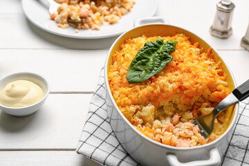 Baking dish with tasty English fish pie on white wooden background