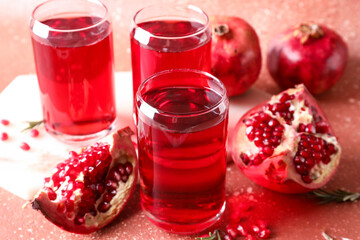 Glasses of delicious pomegranate juice on red background