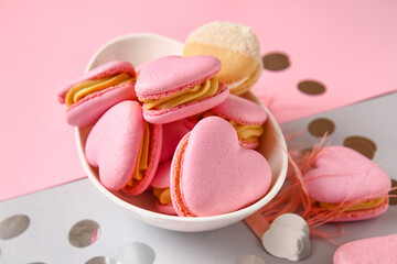 Bowl with tasty heart-shaped macaroons and confetti on color background, closeup