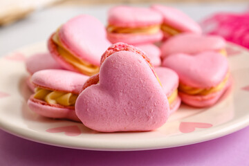 Plate with tasty heart-shaped macaroons on color background, closeup
