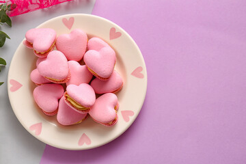 Plate with tasty heart-shaped macaroons on purple background