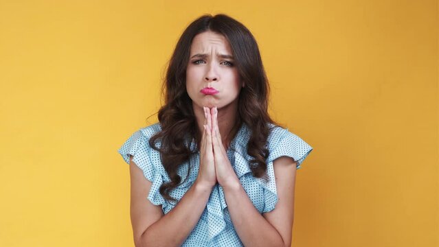 Begging face. Meme woman. Sorry feelings. Sulking pouting lady holding hands asking apologise isolated orange looped video.