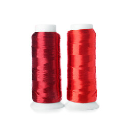 Red sewing thread spools on white background