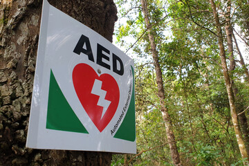 An Automated External Defibrillator, (AED) placed on the tree at a park for prevention of heart attacks patient. - obrazy, fototapety, plakaty