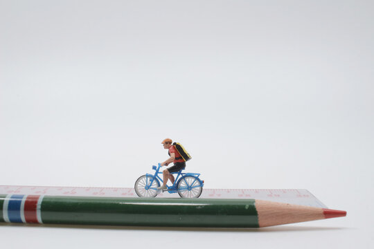 the mini people ride bicycles on wooden ruler.