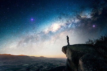 man standing on the rock outdoors, over the valley, staring the Milky Way and shooting stars