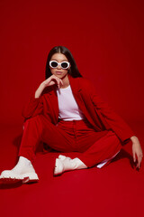 Fashion asian female model in red suit, white boots and sunglasses.