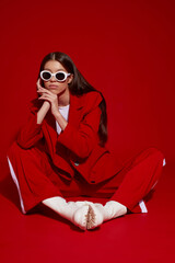Fashion asian female model in red suit, white boots and sunglasses. - 482011655