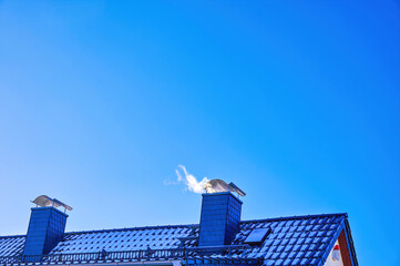 View of a roof with chimneys against a blue sky.